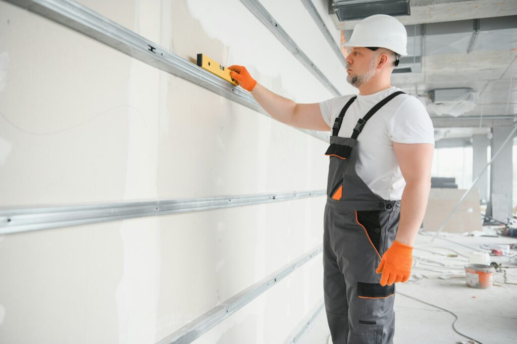 man drywall worker installing plasterboard sheet to wall
